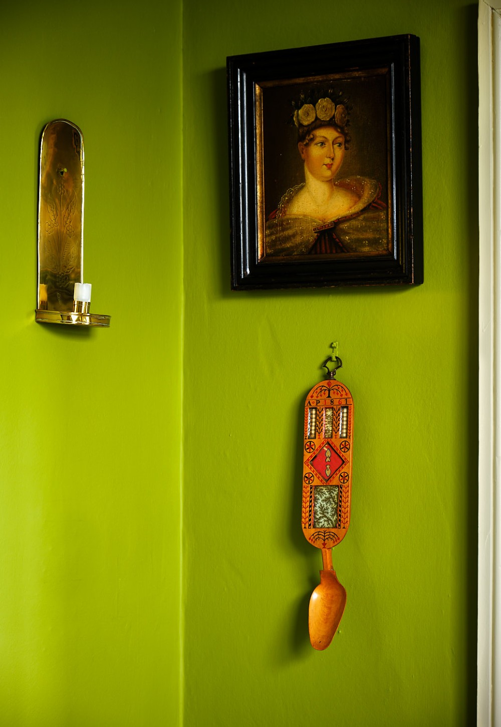 A carved wooden Welsh love spoon featuring polychrome wax inlay, glazed inset panels, incised initials AP, the date 1861, and a brass suspension loop at the top. View VII
