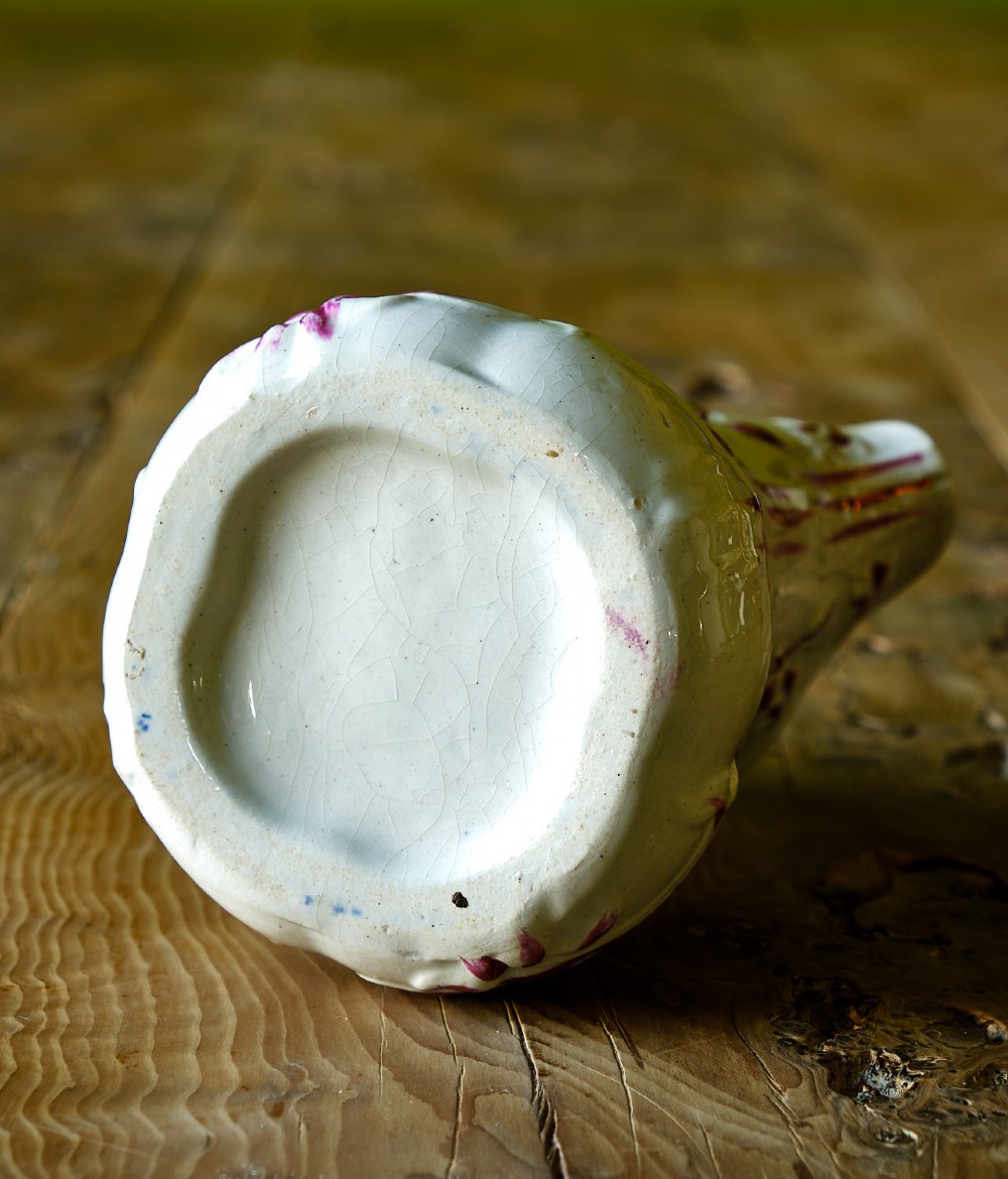 An off-white earthenware pottery jug featuring embossed botanical leaf patterns accented with metallic pink lustre paint. View IV