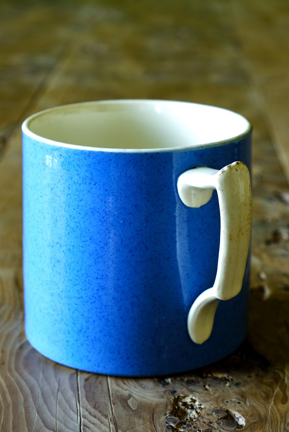A large cylindrical ceramic mug featuring a speckled blue glazed exterior and a light cream interior with a matching handle. View II