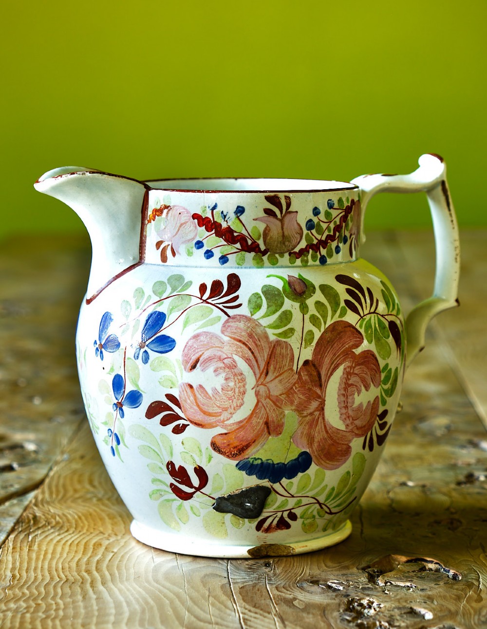 An early nineteenth-century pearlware ceramic jug with hand-painted floral motifs in pink, blue, and green enamels.