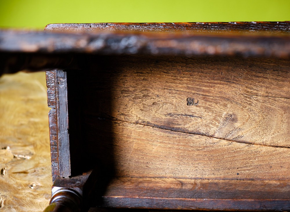 A dark oak seventeenth-century joined stool with a rectangular top, carved apron frieze, turned legs, and low box stretchers. View VII