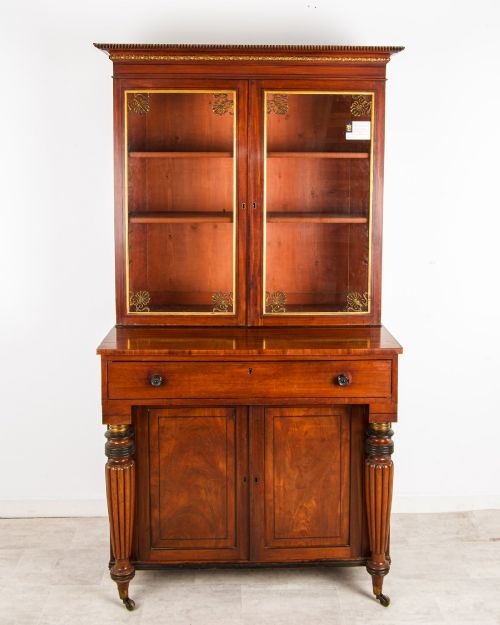 fig 1. An antique Regency mahogany glazed bookcase cabinet with brass decorative mounts, fluted columns, and a lower two-door cupboard.