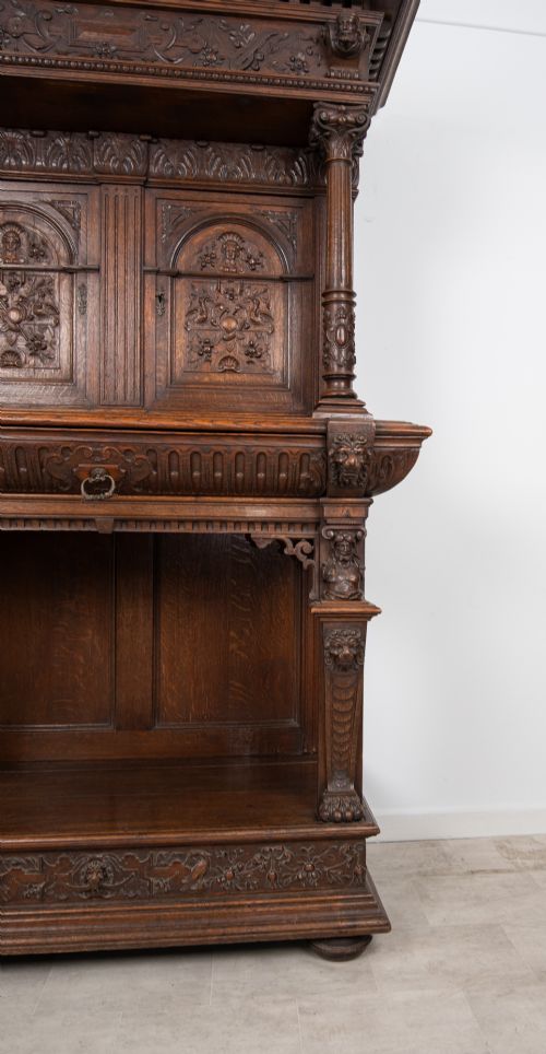 fig 3. A 19th-century carved oak buffet cupboard featuring intricate relief panels, architectural columns, an upper cabinet, and an open lower tier.