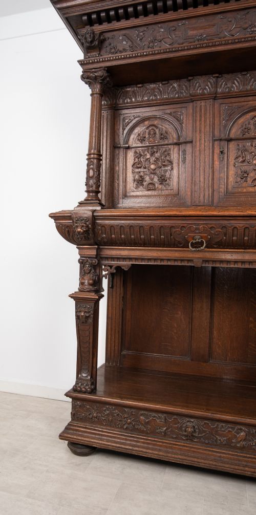 fig 4. A 19th-century carved oak buffet cupboard featuring intricate relief panels, architectural columns, an upper cabinet, and an open lower tier.