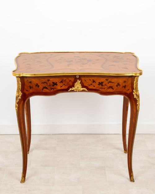 fig 1. A French Louis XV style kingwood bureau plat featuring floral marquetry inlay, curved cabriole legs, and gilt-bronze mounts.