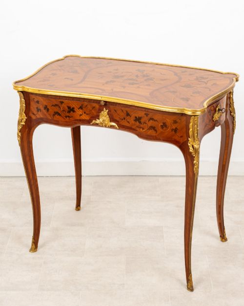 fig 2. A French Louis XV style kingwood bureau plat featuring floral marquetry inlay, curved cabriole legs, and gilt-bronze mounts.