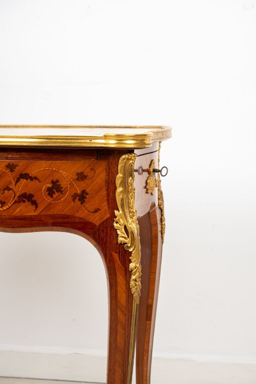 fig 4. A French Louis XV style kingwood bureau plat featuring floral marquetry inlay, curved cabriole legs, and gilt-bronze mounts.