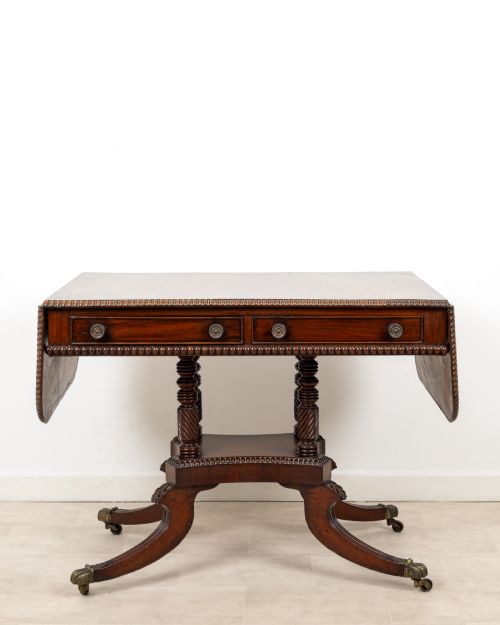 fig 1. A 19th-century mahogany drop-leaf sofa table with four spiral-turned column supports, frieze drawers, and splayed legs on brass castors.
