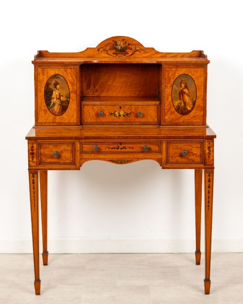 fig 2. An Edwardian hand-painted satinwood writing desk featuring a raised central cupboard superstructure decorated with painted oval portraits, floral swags, and square tapered legs.