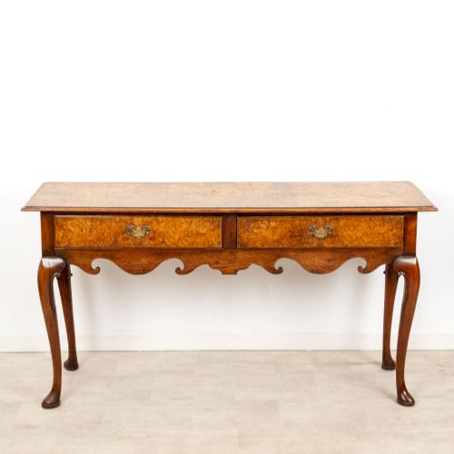 fig 2. A Queen Anne style burr walnut console table featuring two drawers, a shaped apron, and four slender cabriole legs terminating in pad feet.