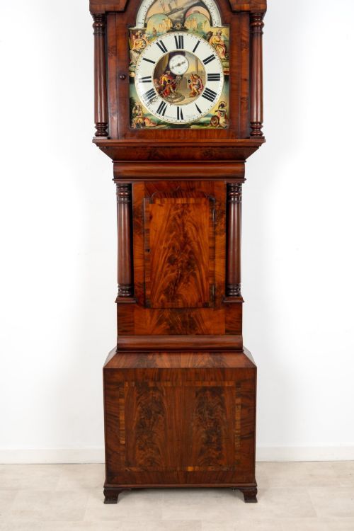 fig 2. An antique mahogany longcase clock featuring a swan-neck pediment, turned columns, and a hand-painted arch dial with a moon phase display.