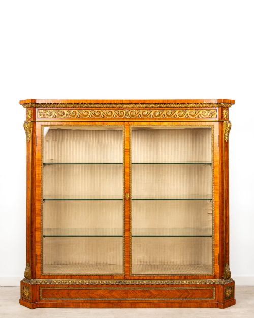 fig 1. A large veneered display cabinet featuring gilt-bronze mounts, glazed twin doors, glass shelving, and a fabric-lined interior.