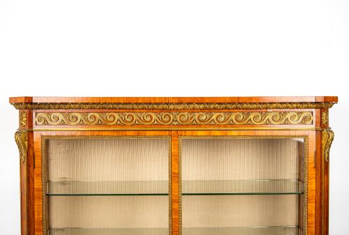 fig 2. A large veneered display cabinet featuring gilt-bronze mounts, glazed twin doors, glass shelving, and a fabric-lined interior.