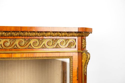 fig 3. A large veneered display cabinet featuring gilt-bronze mounts, glazed twin doors, glass shelving, and a fabric-lined interior.