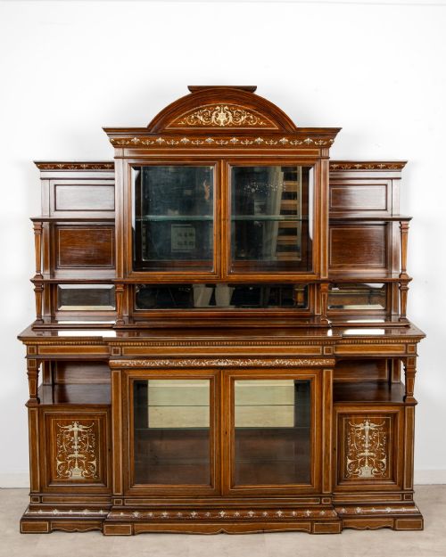 fig 1. A large late Victorian rosewood display cabinet featuring intricate inlay work, glazed upper and lower doors, an arched pediment, and mirrored back panels.