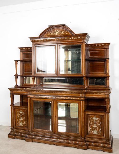 fig 2. A large late Victorian rosewood display cabinet featuring intricate inlay work, glazed upper and lower doors, an arched pediment, and mirrored back panels.