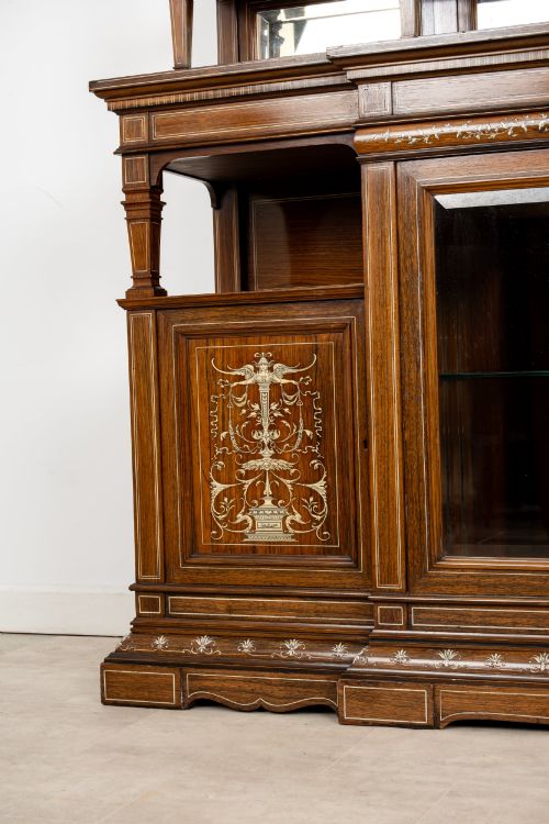 fig 5. A large late Victorian rosewood display cabinet featuring intricate inlay work, glazed upper and lower doors, an arched pediment, and mirrored back panels.