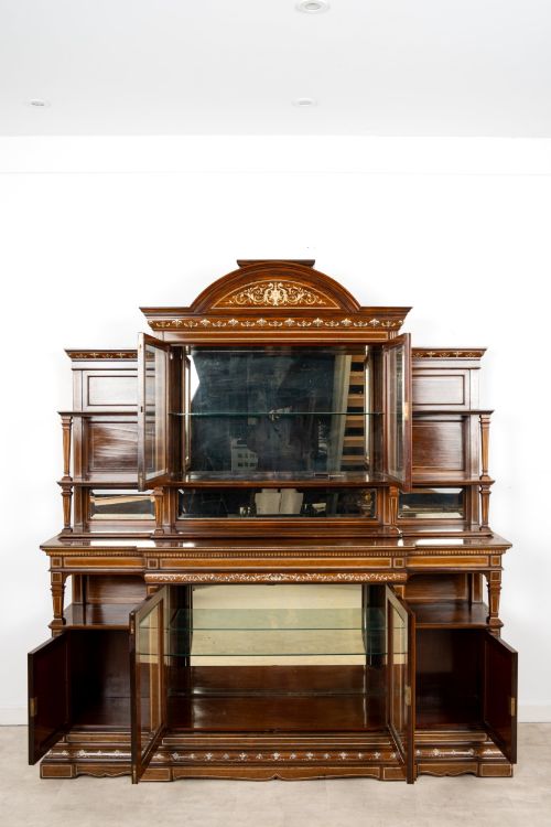 fig 8. A large late Victorian rosewood display cabinet featuring intricate inlay work, glazed upper and lower doors, an arched pediment, and mirrored back panels.