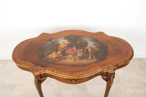 fig 1. A French Louis XV style centre table featuring a serpentine glass-covered top with a painted figurative scene, cabriole legs, and ornate gilt bronze mounts.