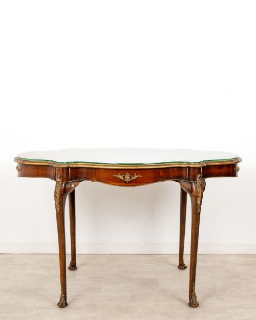fig 2. A French Louis XV style centre table featuring a serpentine glass-covered top with a painted figurative scene, cabriole legs, and ornate gilt bronze mounts.
