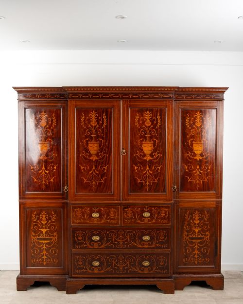 fig 1. An Edwardian mahogany compactum wardrobe featuring classical urn marquetry inlay, side hanging sections, central drawers, and panelled cupboard doors.