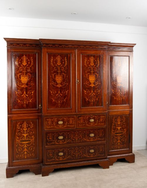 fig 3. An Edwardian mahogany compactum wardrobe featuring classical urn marquetry inlay, side hanging sections, central drawers, and panelled cupboard doors.