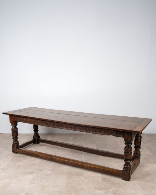 fig 1. A long 18th-century oak refectory dining table featuring a carved lunette frieze, turned baluster legs, and sturdy box stretchers.