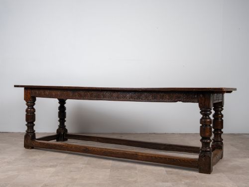 fig 2. A long 18th-century oak refectory dining table featuring a carved lunette frieze, turned baluster legs, and sturdy box stretchers.