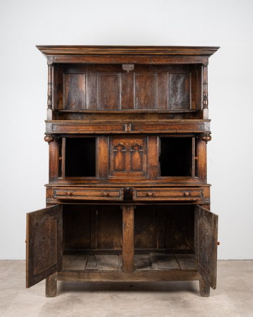 fig 2. A dark oak three-tier Welsh cwpwrdd tridarn featuring an open upper canopy, middle cupboard section with raised arch panels and turned pillars, and a base cupboard with two drawers.
