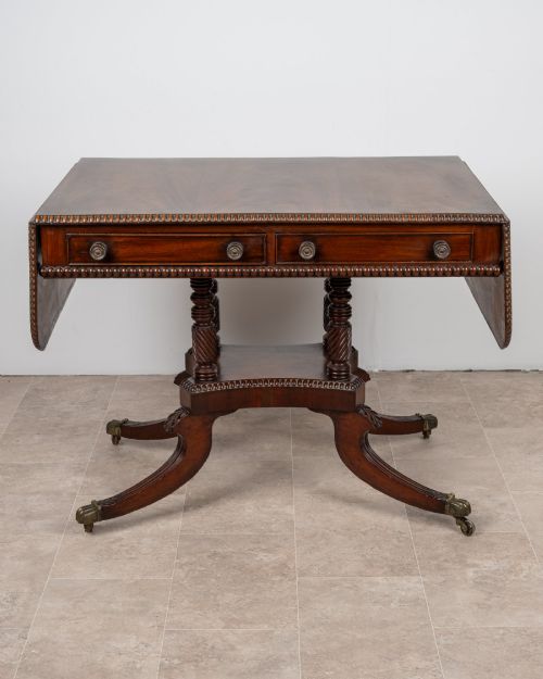 fig 1. An antique Regency mahogany drop-leaf sofa table with two drawers, spiral-turned column supports, and splayed legs on brass castors.
