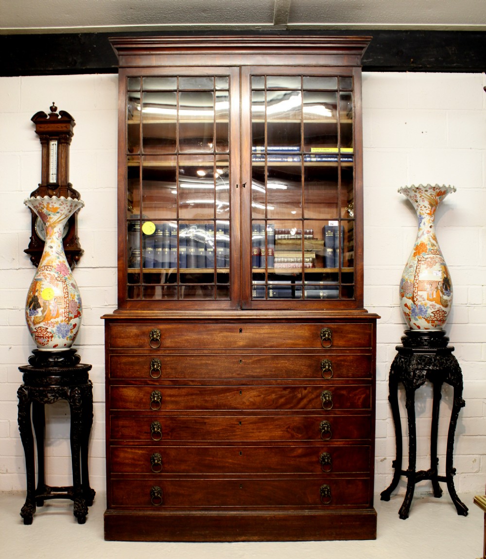 A Georgian mahogany secretaire bookcase featuring a glazed two-door upper cabinet with astragal glazing bars over a lower chest of drawers with brass lion-mask handles.