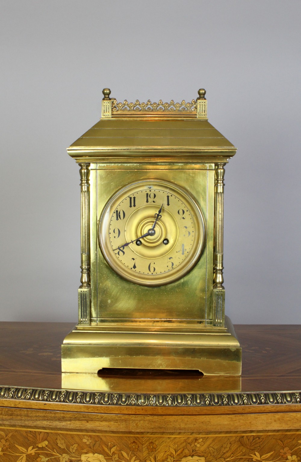 A Victorian brass mantel clock featuring fluted corner columns, top gallery cresting, and an Arabic numeral dial.