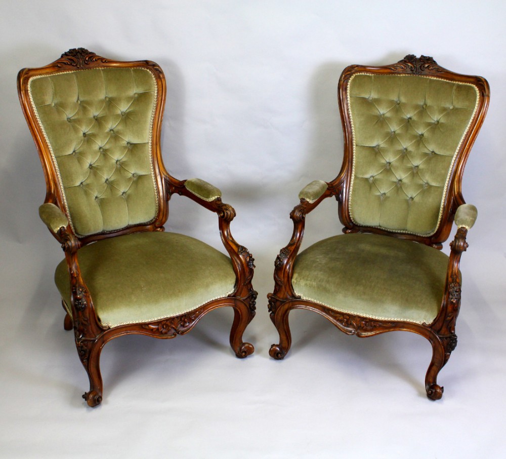 A PAIR OF VICTORIAN WALNUT CARVED OPEN ARM CHAIRS  