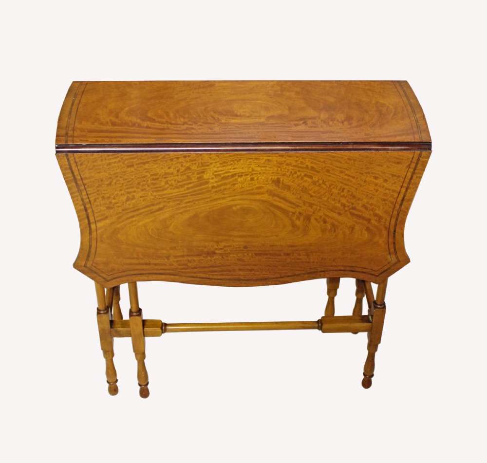 An antique satinwood Pembroke table featuring crossbanded edging, two drop leaves, turned spindle legs, and a low stretcher rail.
