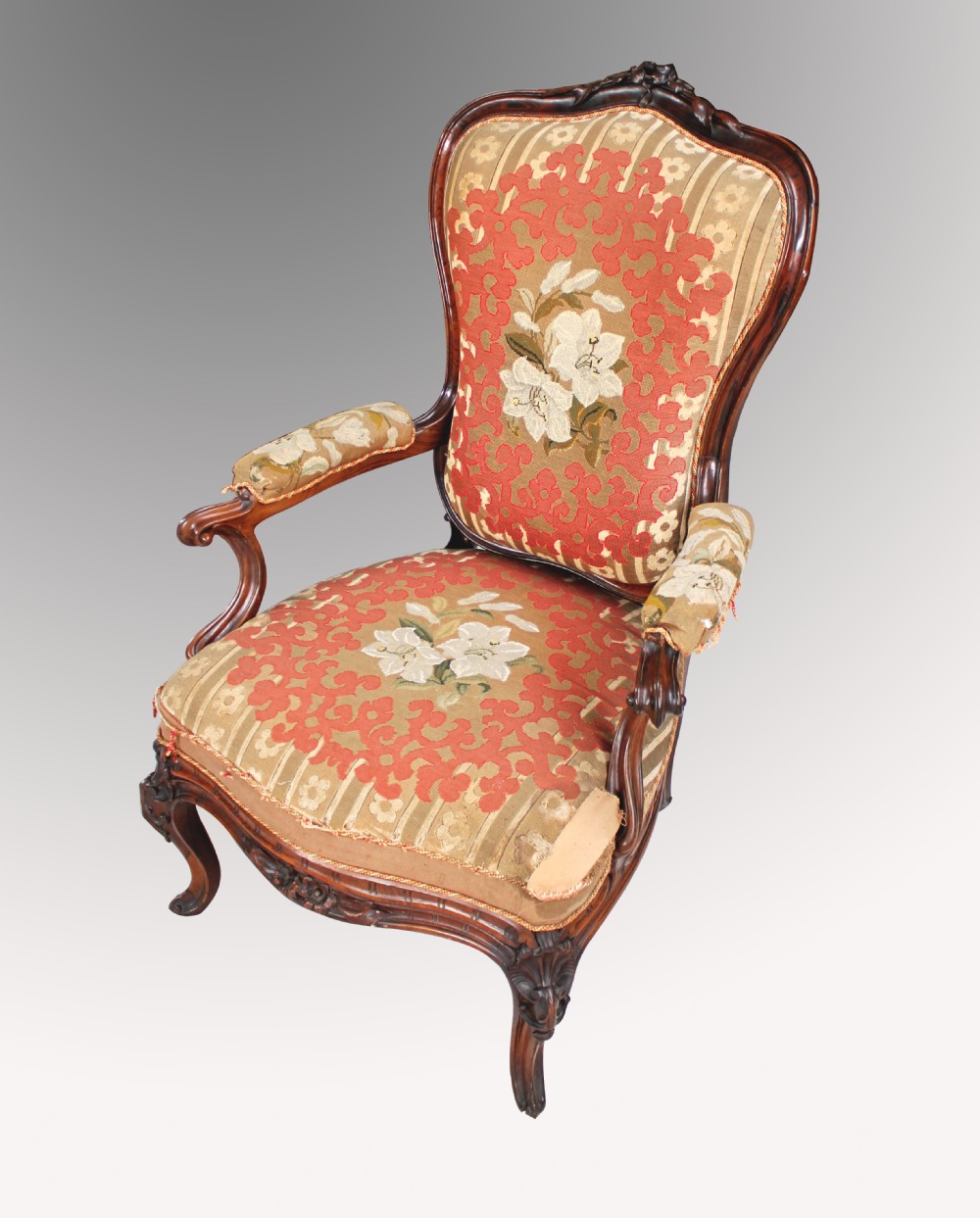 A 19th-century French carved rosewood armchair featuring floral tapestry upholstery, padded armrests, and cabriole legs.