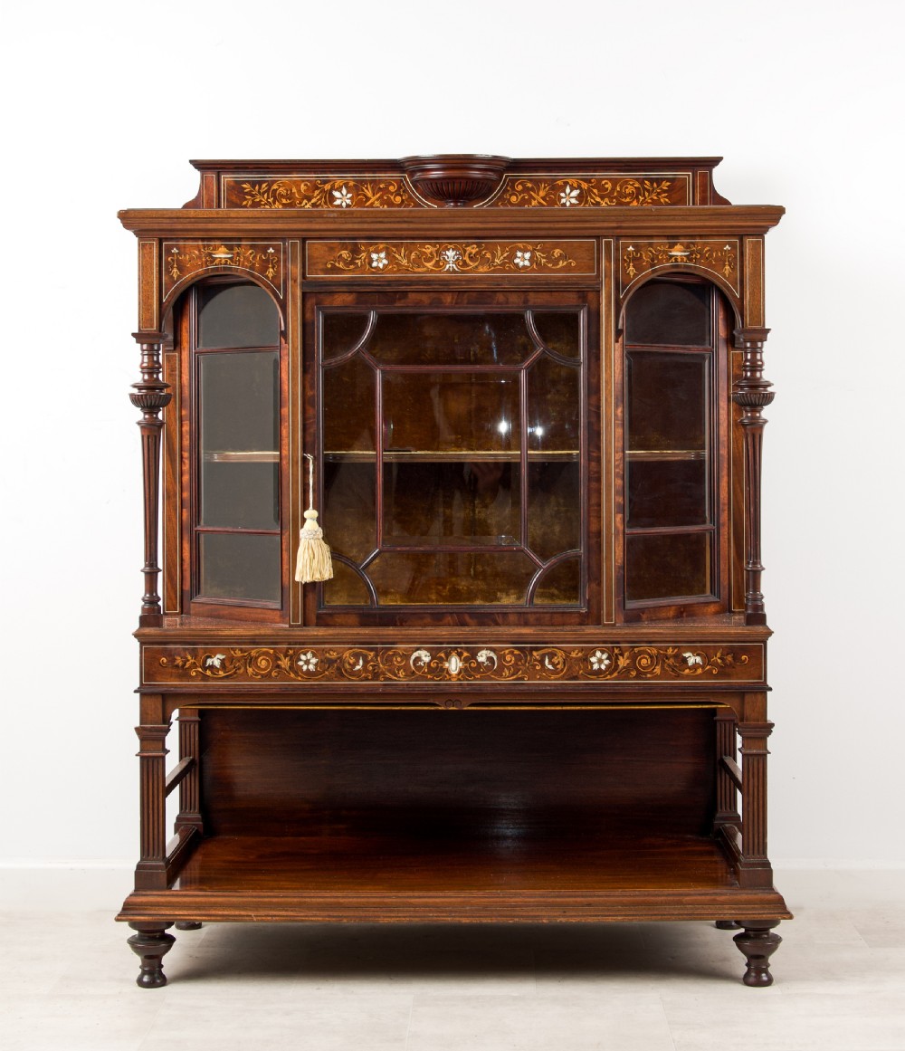 A Victorian dark brown timber display cabinet featuring intricate floral marquetry inlay, glazed central doors with geometric glazing bars, and an open lower shelf.
