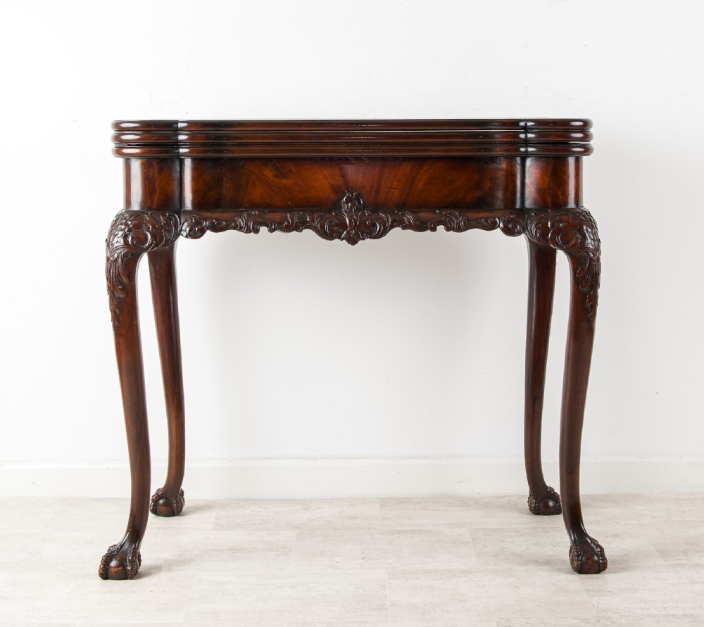 A dark mahogany George II style dual-action tea and card table with carved cabriole legs and ball and claw feet.