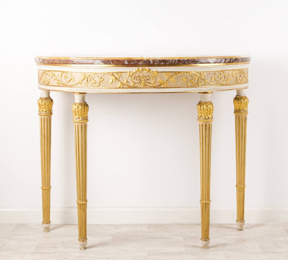 A Georgian style demi-lune console table featuring a rouge marble top, gilded foliate carved apron, and four fluted tapered legs. View II