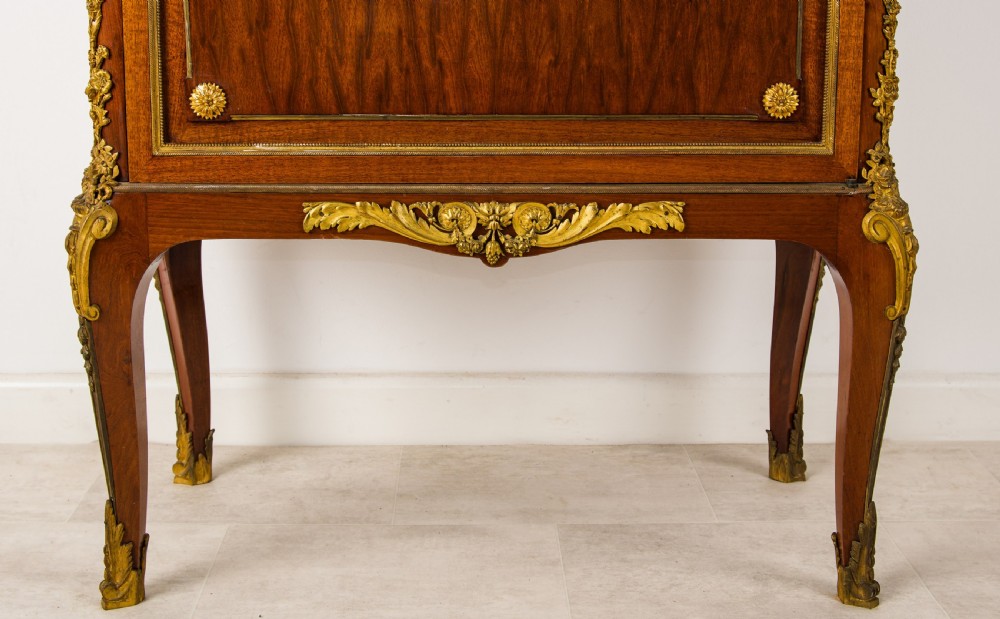 A French mahogany vitrine cabinet featuring glass shelves, ornate gilt-bronze mounts, cabriole legs, a mirrored back interior, and a marble top. View VIII