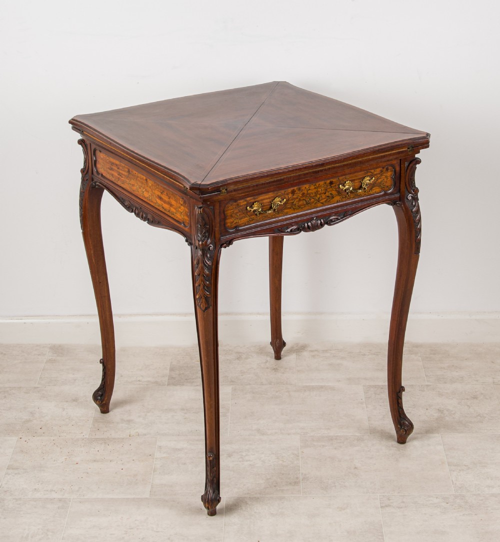 A 19th-century mahogany envelope games table with floral marquetry inlay, cabriole legs, and a single drawer with brass pulls.
