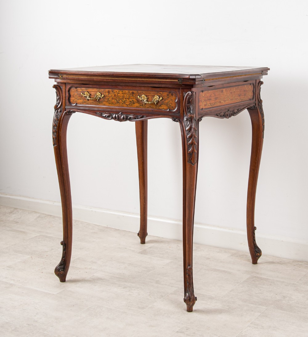 A 19th-century mahogany envelope games table with floral marquetry inlay, cabriole legs, and a single drawer with brass pulls. View IV