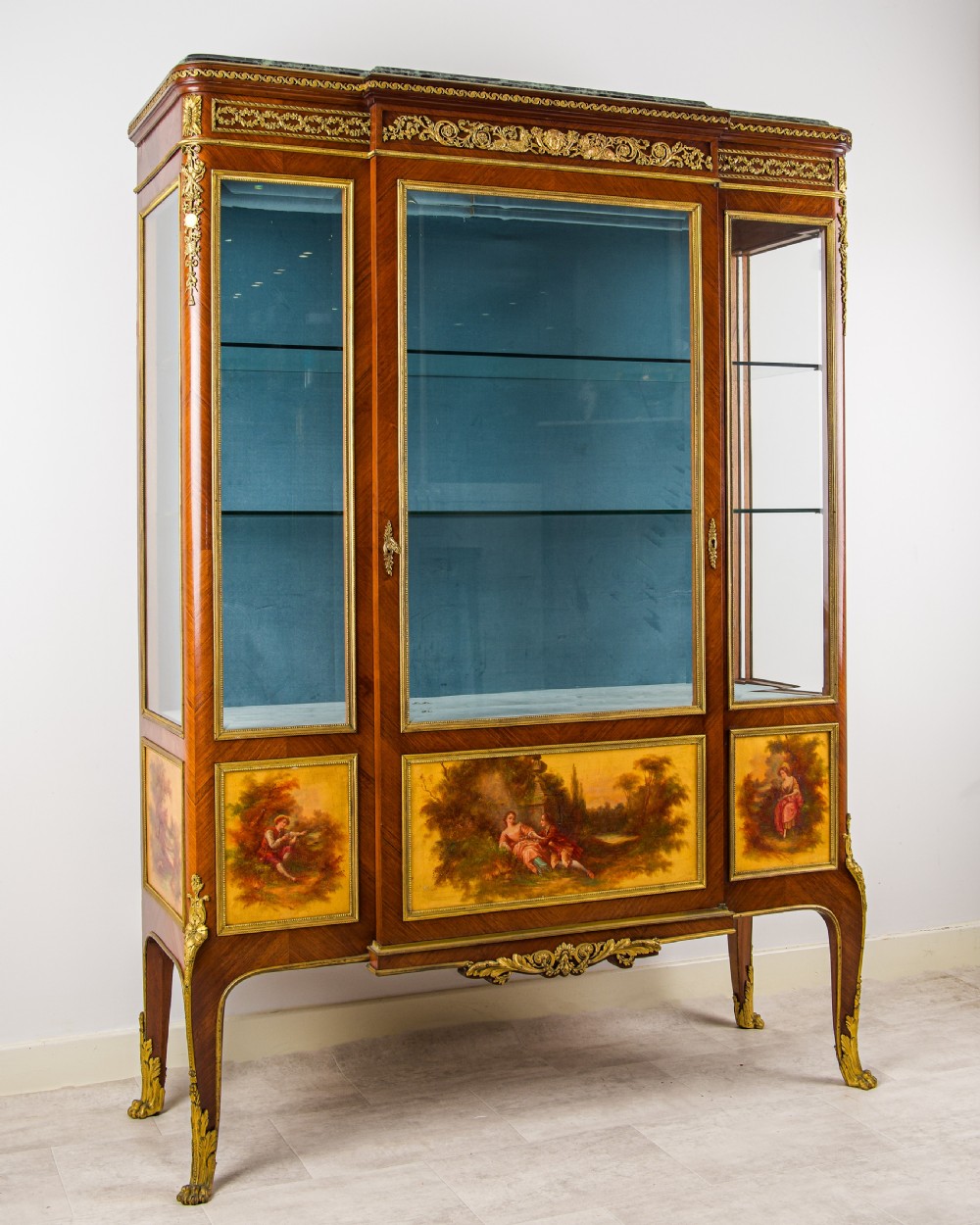A French kingwood vitrine cabinet featuring glass display doors, gilt bronze mounts, a green marble top, blue fabric lining, and hand-painted Vernis Martin panels at the base. View II