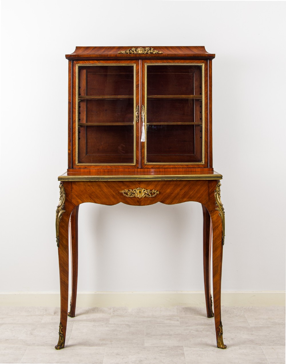 A 19th-century French kingwood bonheur du jour writing cabinet with glazed upper doors, ornate gilt-bronze mounts, and cabriole legs. View II