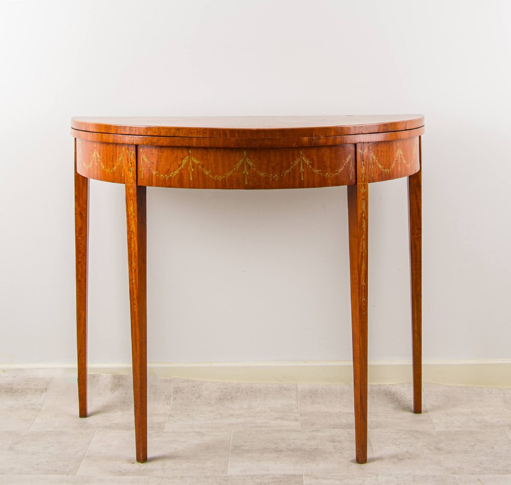 An antique satinwood demi-lune games table featuring hand-painted floral medallions and swags across the fold-over top and frieze. View III