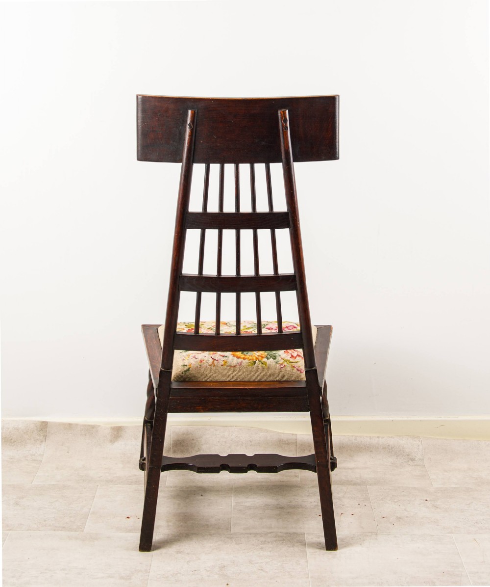 An antique dark oak Arts and Crafts side chair featuring a carved high backrest, spindle grid detailing, twisted front legs, and a needlepoint floral seat. View VII