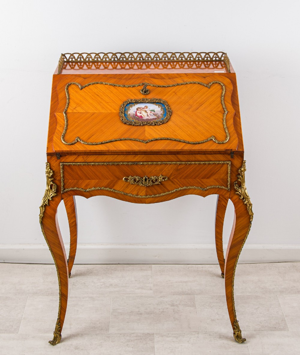 An antique French Louis XV style kingwood writing bureau with a slant-front lid featuring a central painted porcelain plaque, brass top gallery, cabriole legs, and gilded ormolu mounts. View V