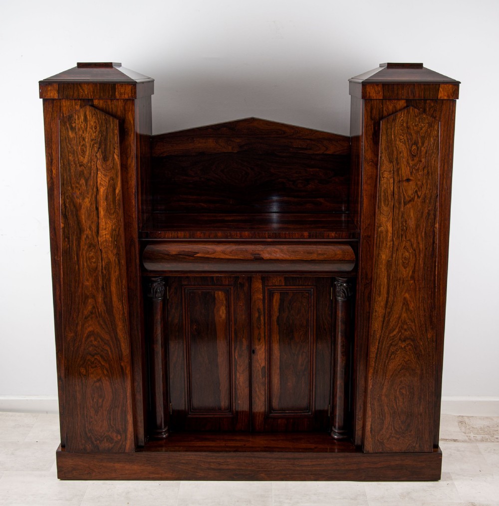 An antique William IV dark rosewood side cabinet featuring twin flanking pedestal towers, a central cupboard with panelled doors, turned column accents, and a low backboard. View II
