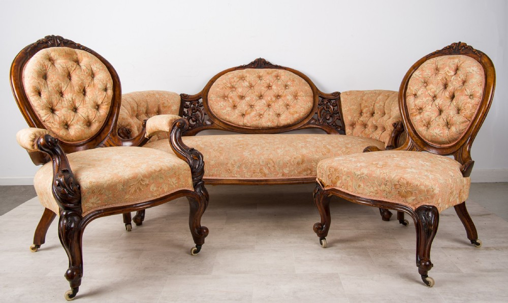 An antique Victorian three-piece seating suite featuring a carved walnut settee and two matching armchairs upholstered in peach damask fabric with button-tufted backs and cabriole legs. View II