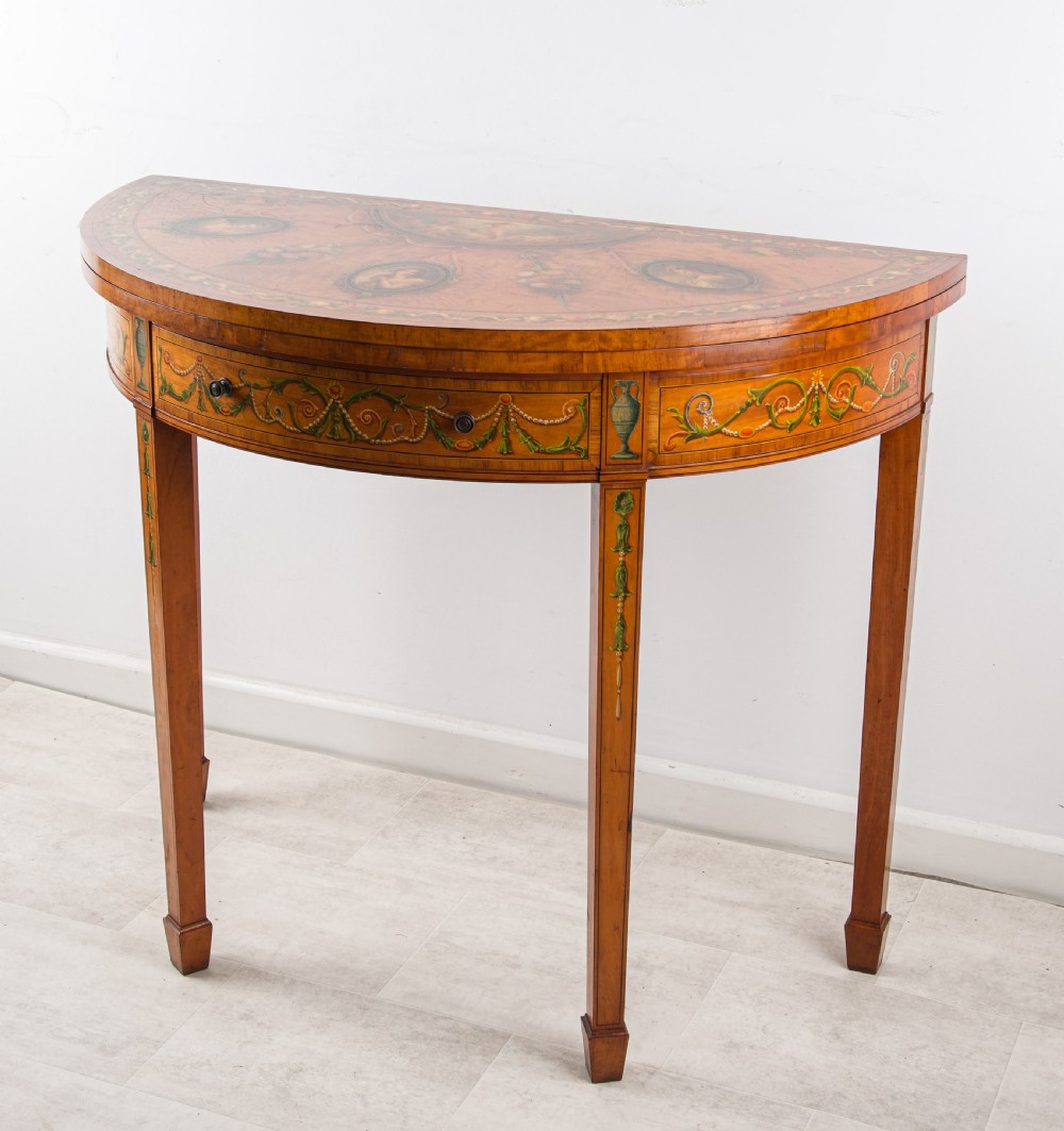 A nineteenth-century demi-lune satinwood card table featuring hand-painted classical portrait medallions, floral swags, and square tapered legs. View II