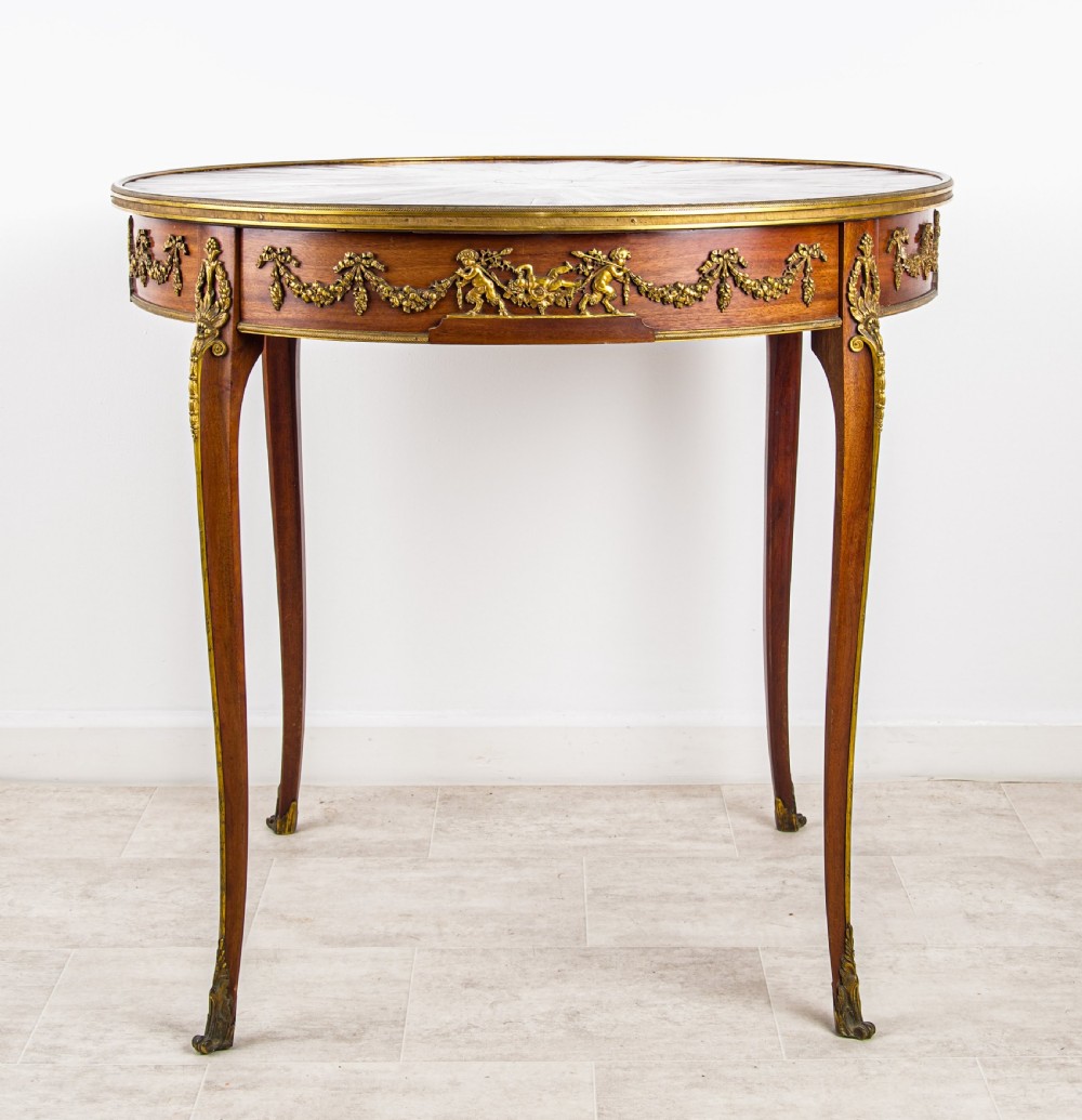 A circular French centre table featuring a sunburst marquetry veneer top, slender cabriole legs, and ornate gilt bronze mounts around the apron. View II